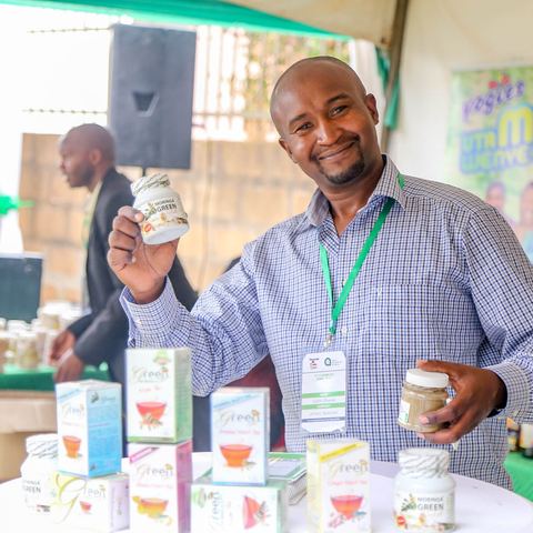 An entrepreneur holding up a jar of his packaged product at an exhibition stand