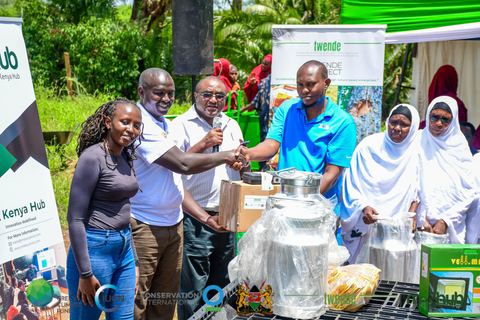 Community members and project staff gathered around new milk cans at a TWENDE equipment handover