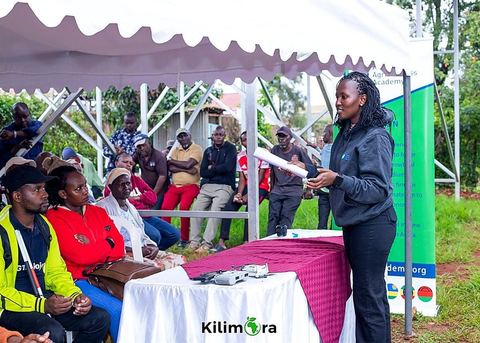 An AAA trainer addressing farmers seated under a tent at the ACSH Community Garden